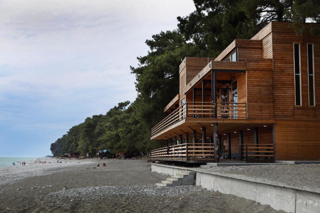 a wooden building on a beach next to the ocean at Hotel Kiparis in Pizunda