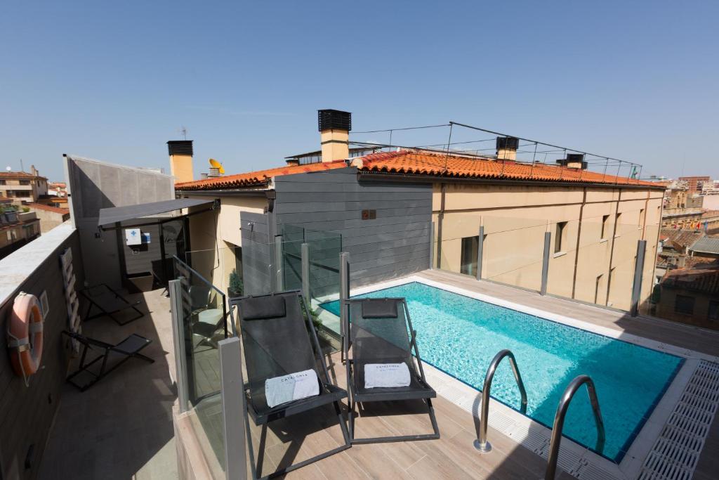 a balcony with two chairs and a swimming pool at Catalonia Plaza Mayor Salamanca in Salamanca