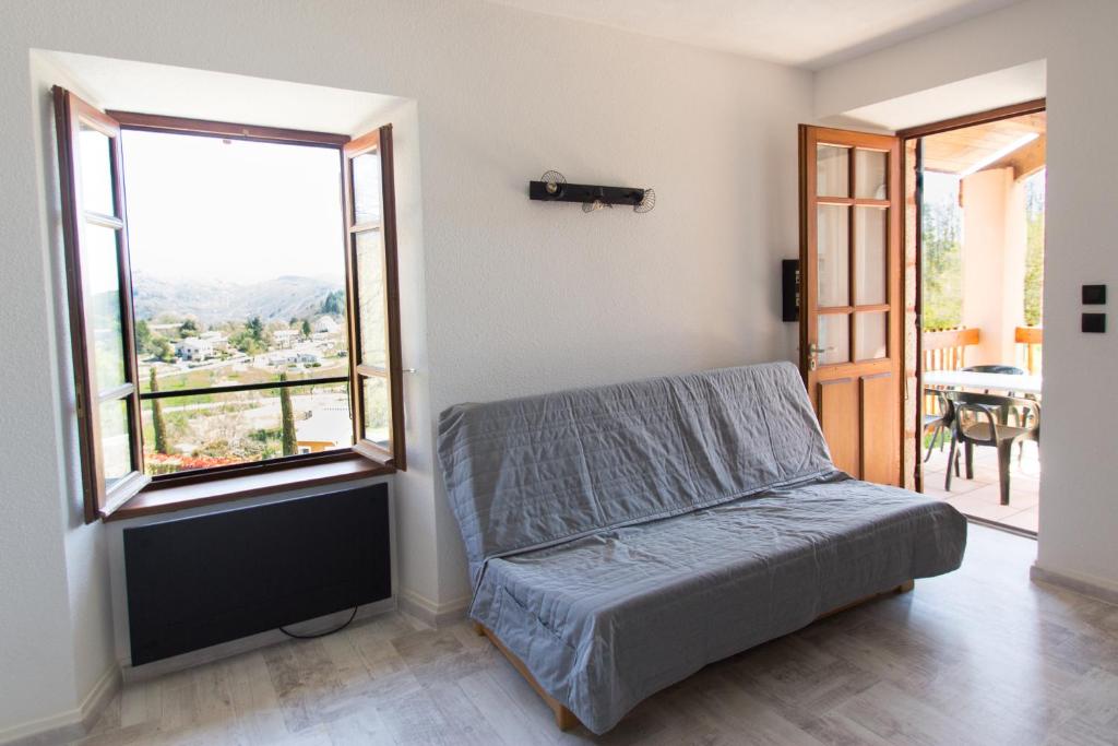 a bedroom with a bed and a large window at Auberge Les Grillons in Meyras