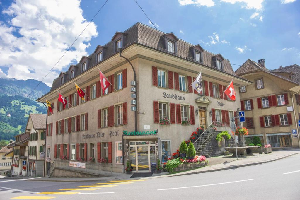 a building with flags in front of it on a street at Hotel Landhaus Adler in Frutigen