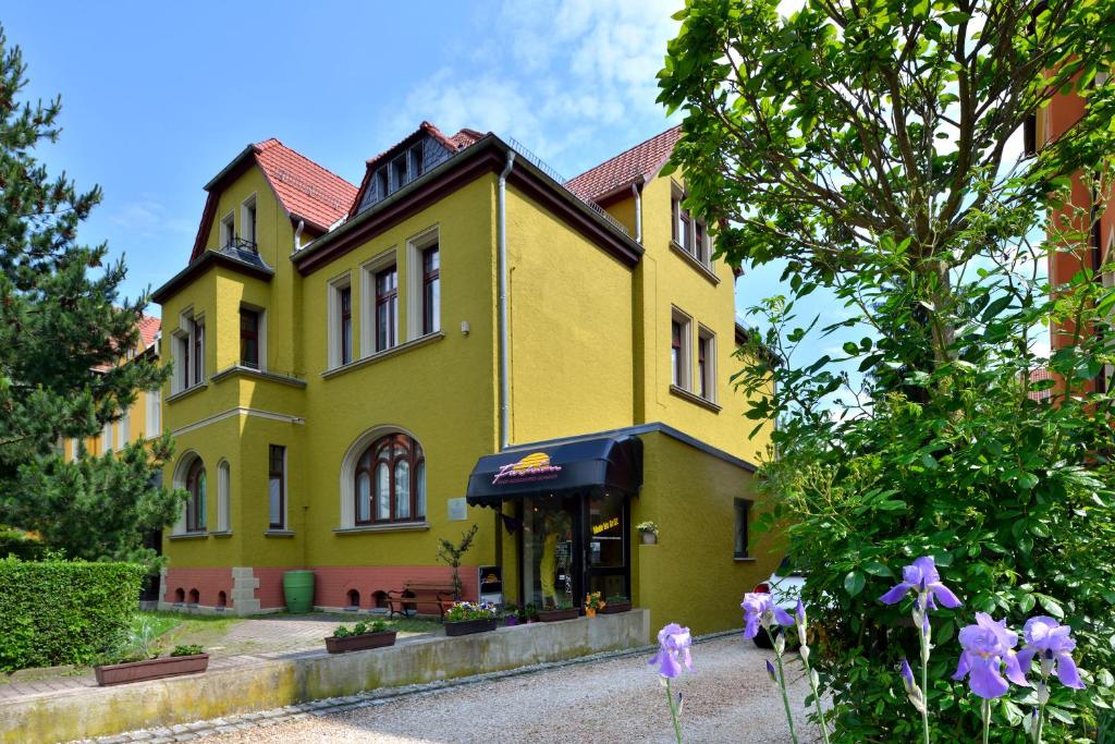 una casa amarilla con flores púrpuras delante de ella en Schlossblick Apartment en Gotha