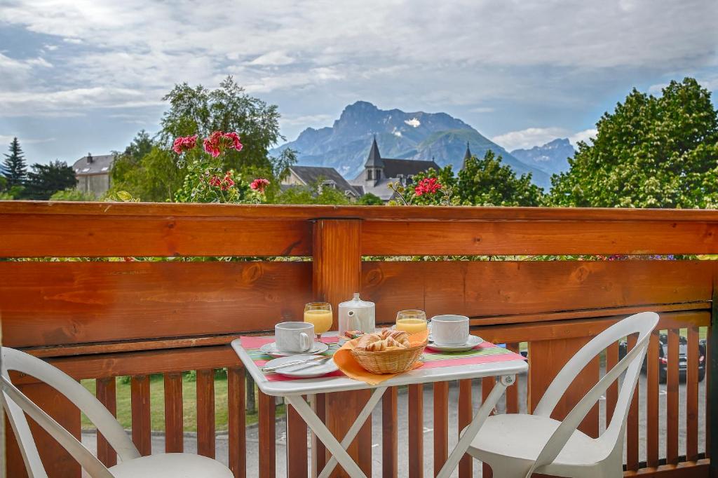 a table and chairs on a balcony with a view of mountains at Logis Murtel in La Mure