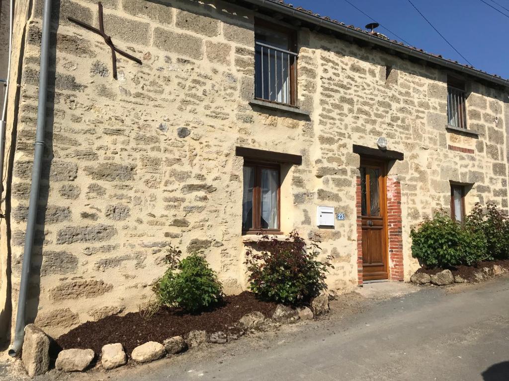 um edifício de pedra com uma porta e duas janelas em Maison de charme em Concourson-sur-Layon