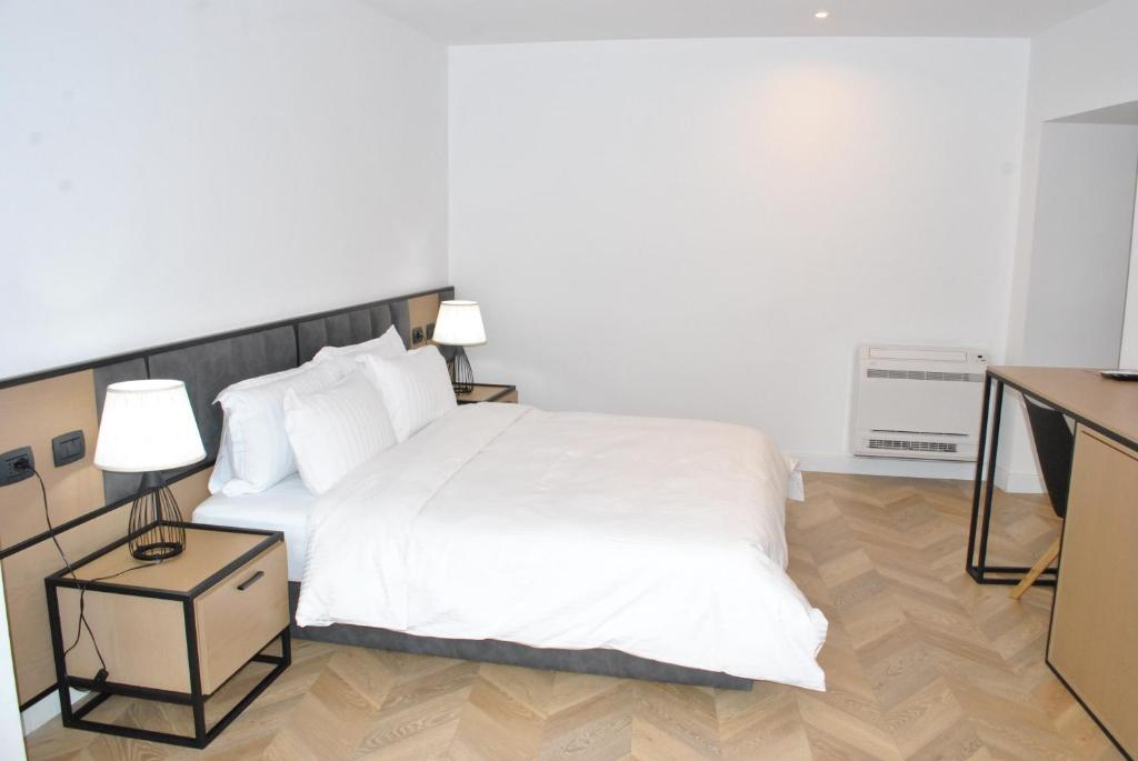 a bedroom with a large white bed and a desk at Prime Hotel in Tirana