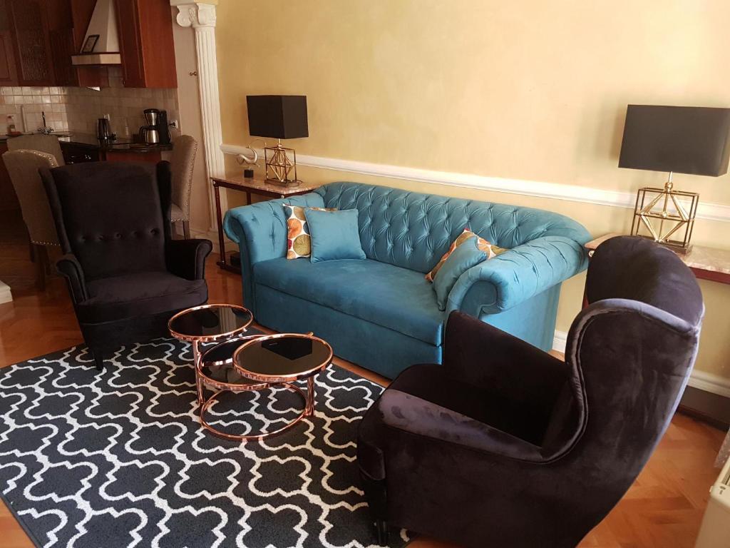 GoldStar Luxury Old Town Krakow Apartment في كراكوف: غرفة معيشة مع أريكة زرقاء وكرسيين