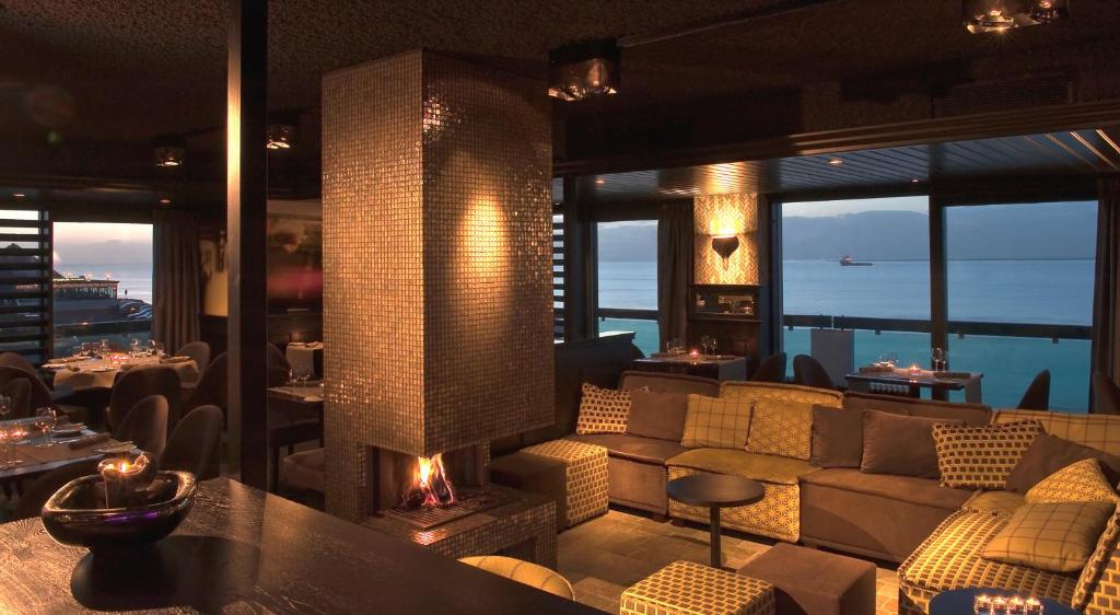 a restaurant with a fireplace and a view of the ocean at Grand Hotel Beatrix in Den Helder