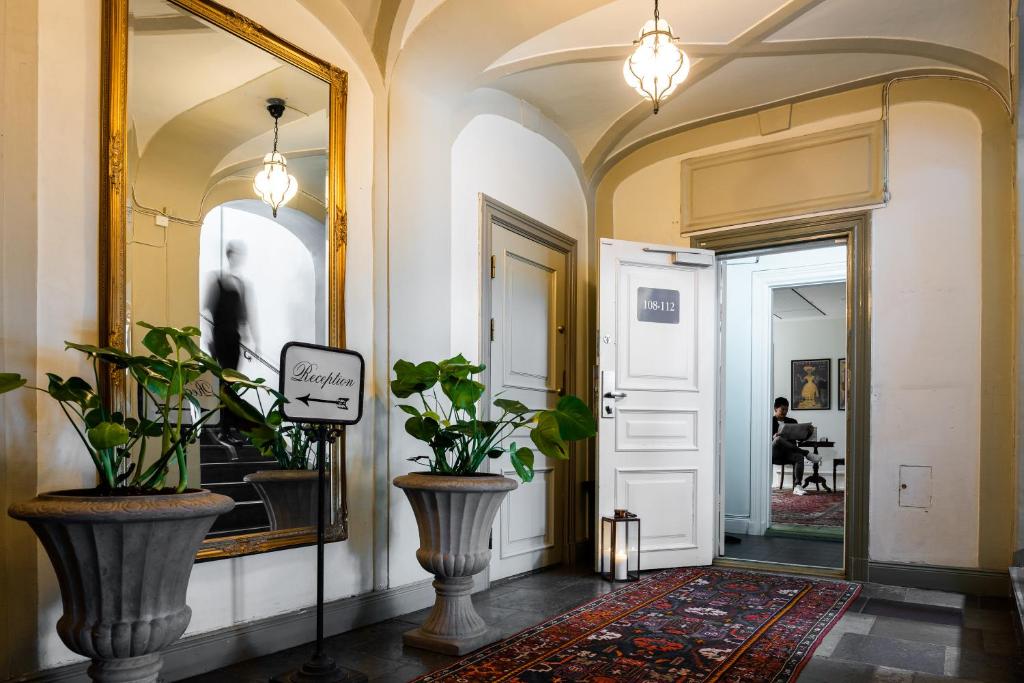 einen Flur mit zwei großen Vasen und einem Spiegel in der Unterkunft Castle House Inn in Stockholm