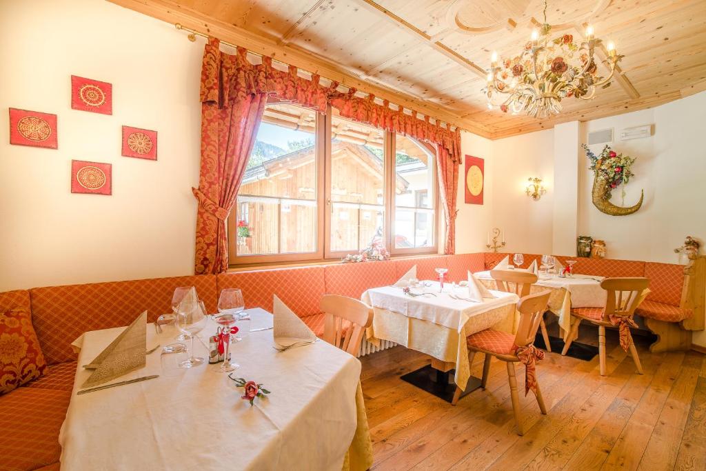 restauracja ze stołami i krzesłami oraz żyrandolem w obiekcie Pineta Pastry Hotel w mieście Rocca Pietore