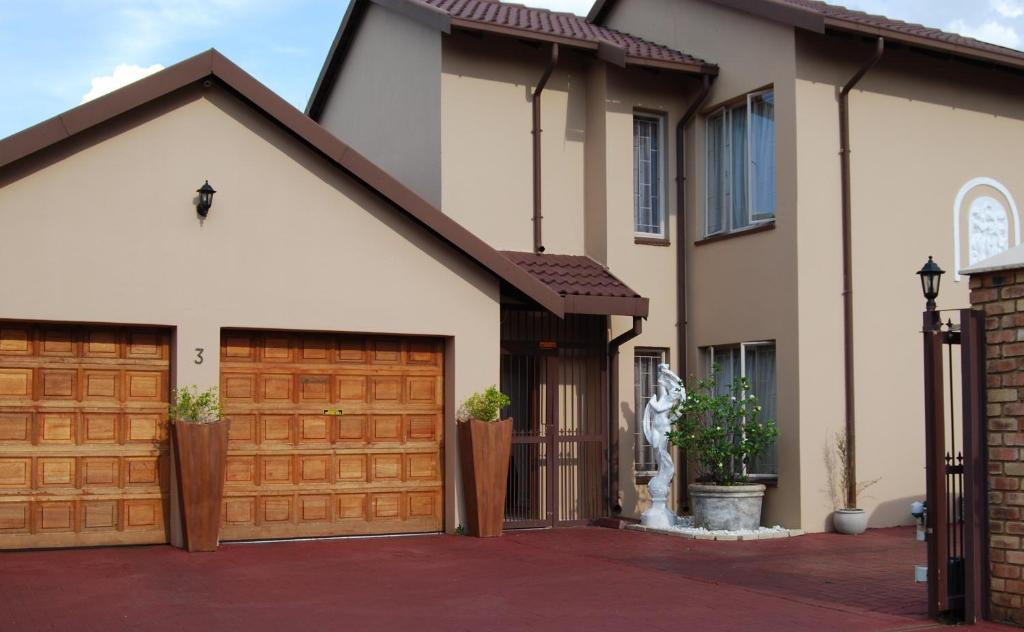 a house with wooden garage doors in a driveway at Pilgrims Delight Guest House in Centurion