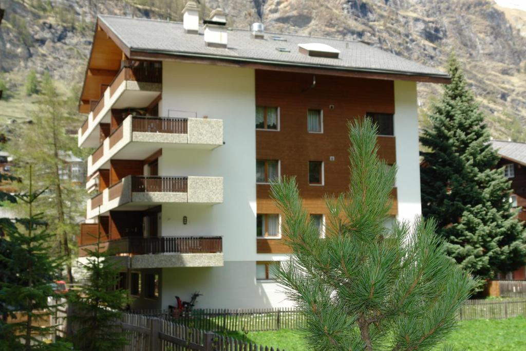 un bâtiment avec des balcons et des arbres devant une montagne dans l'établissement Myzermatt Monazit, à Zermatt