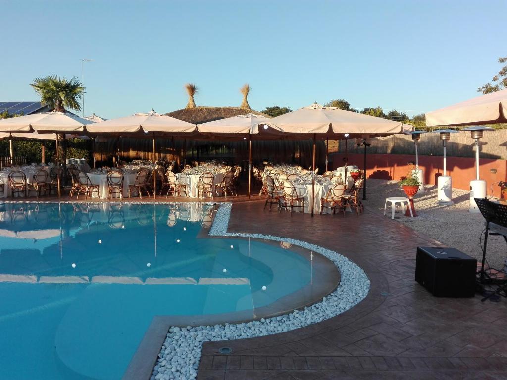 een zwembad met tafels, stoelen en parasols bij Agriturismo La Valle Di Ceri in Cerveteri