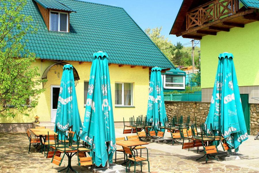 a group of tables and chairs with blue umbrellas at Перлина Дністра in Rudkovtsy