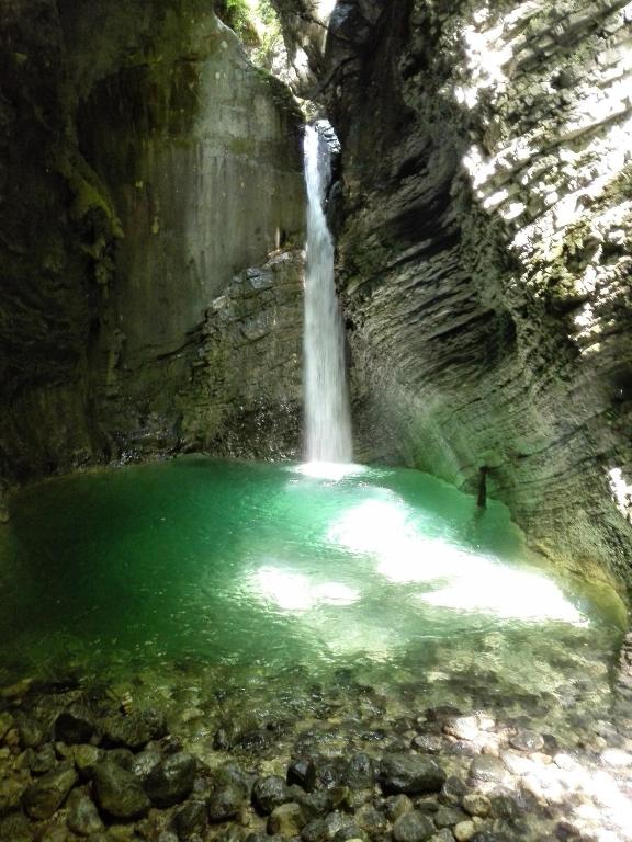 a waterfall in a cave with a pool of green water at Apartments Bobi in Tolmin