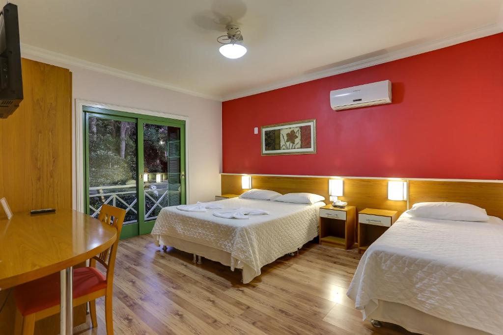 um quarto com duas camas e uma parede vermelha em Vila Rica Pousada em Nova Petrópolis