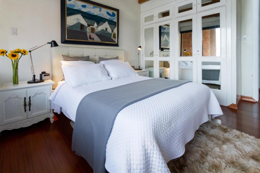 a white bedroom with a large white bed and a window at Penthouse Lodge B&B in Quito