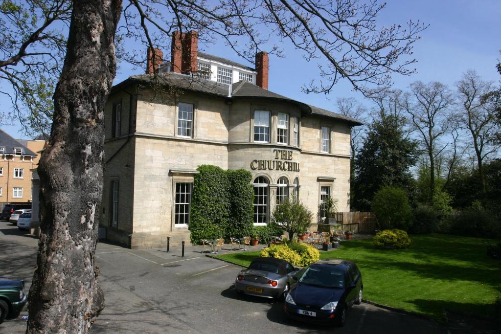 un edificio con coches estacionados frente a él en The Churchill Hotel, en York