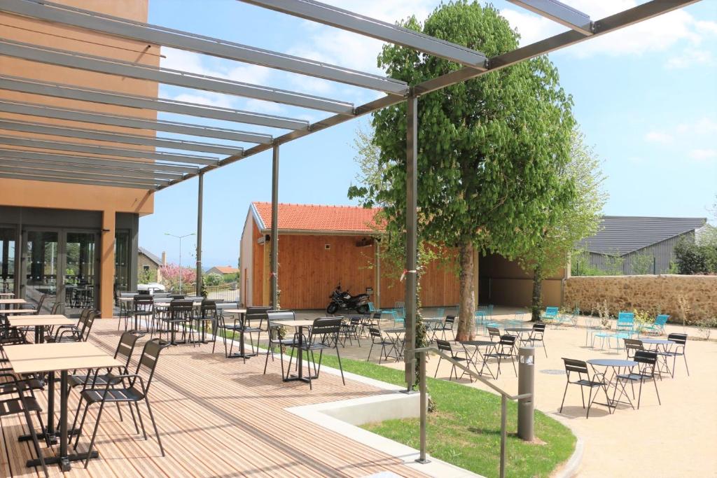 a patio with tables and chairs in front of a building at Le Felicien in Saint-Félicien