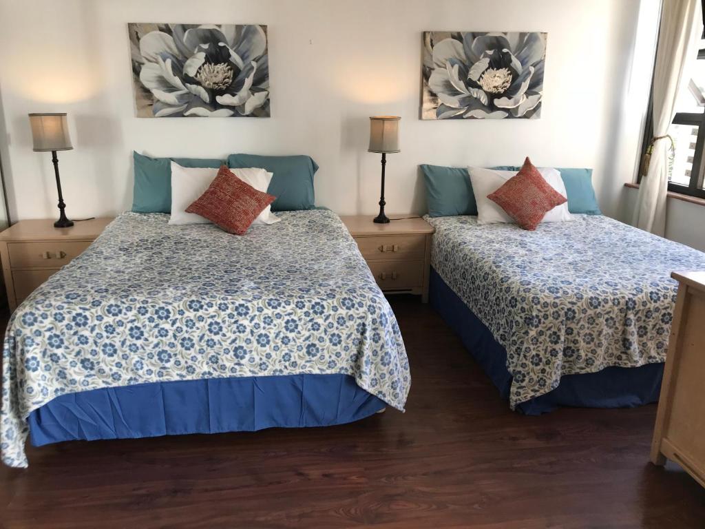 1 dormitorio con 2 camas y 2 lámparas en Waikiki Banyan en Honolulu