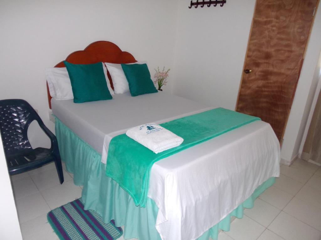 a bedroom with a bed with green and white pillows at Hotel Monaco De Riohacha in Ríohacha