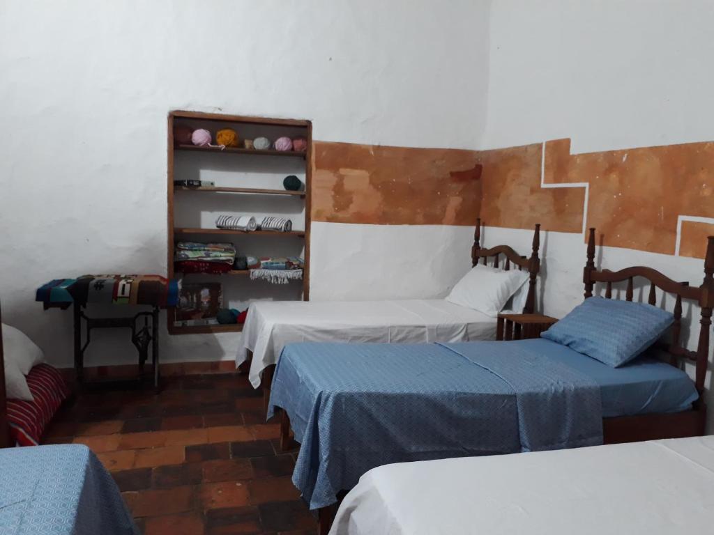 a room with three beds and a shelf with at la casa de la nona in San Gil