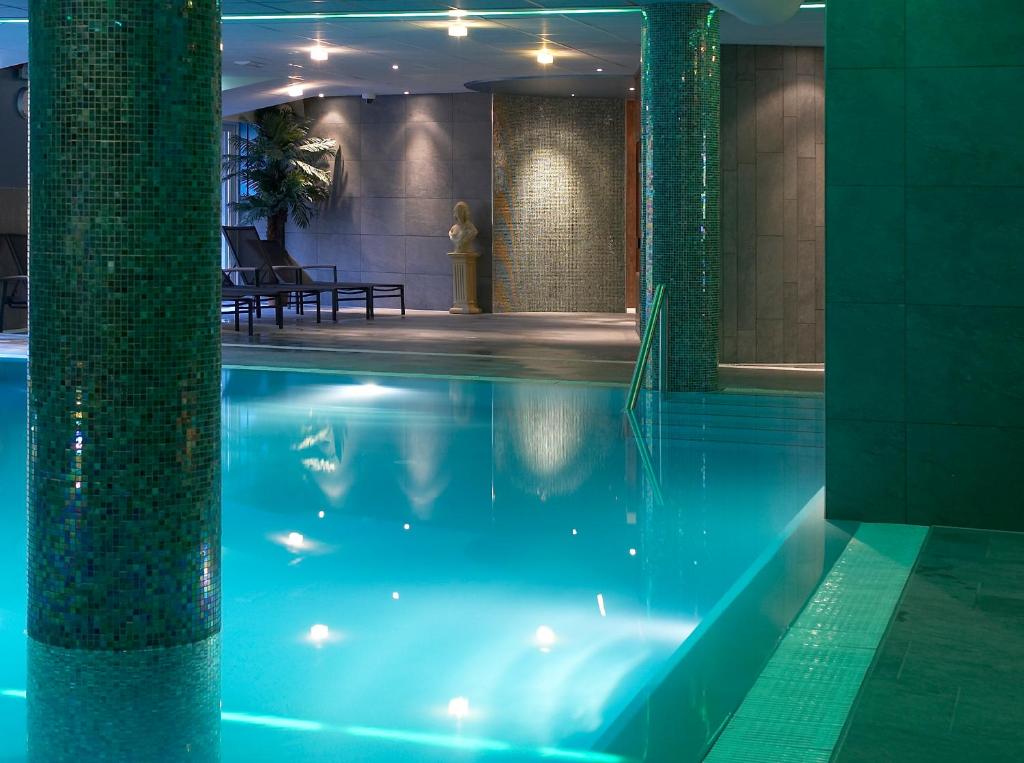 a swimming pool in a building with blue water at Hotel & Appartementen - De Zeven Heuvelen in Groesbeek