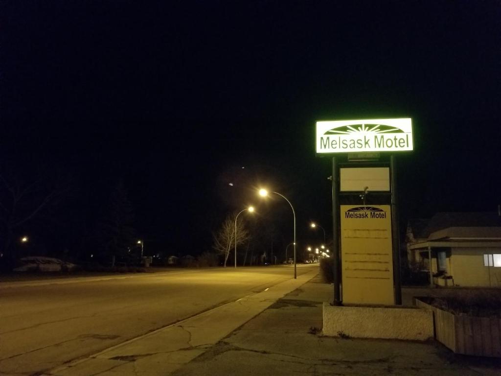 a sign for a gas station on a street at night at Melsask Motel in Melville