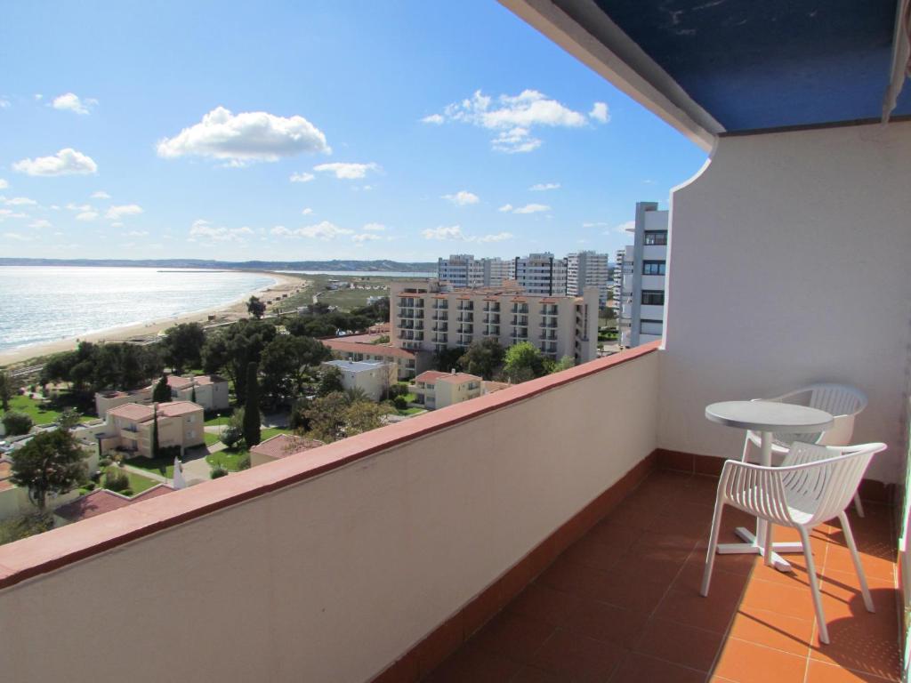 uma varanda com uma mesa e vista para a praia em Apartamentos vista mar em Alvor