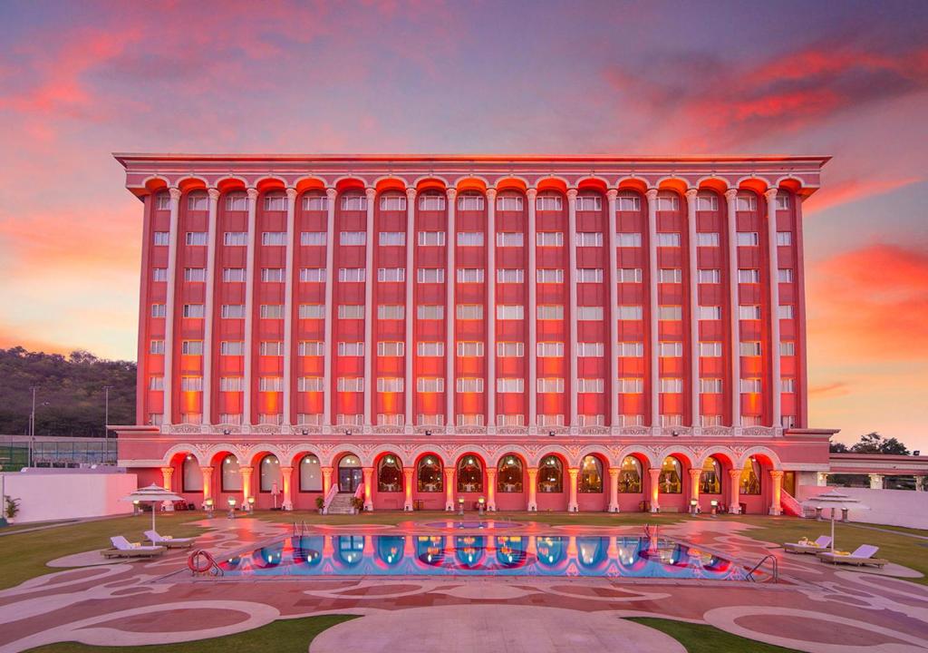 um grande edifício vermelho com uma piscina em frente em Ramoji Film City- Sitara Luxury Hotel em Pedda Ambarpet