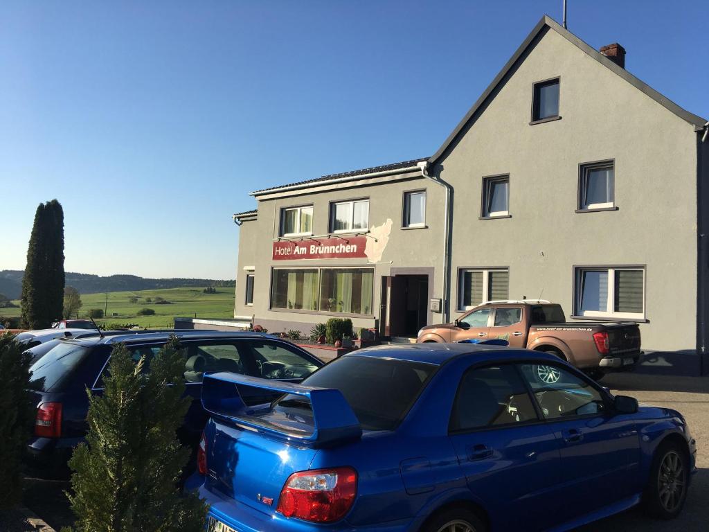 two cars parked in a parking lot in front of a building at Hotel am Brünnchen in Oberbaar