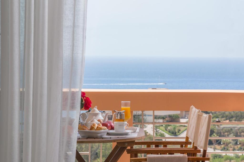 stół z jedzeniem i napojami na balkonie z widokiem na ocean w obiekcie Comfortable house with amazing view w mieście Anavissos