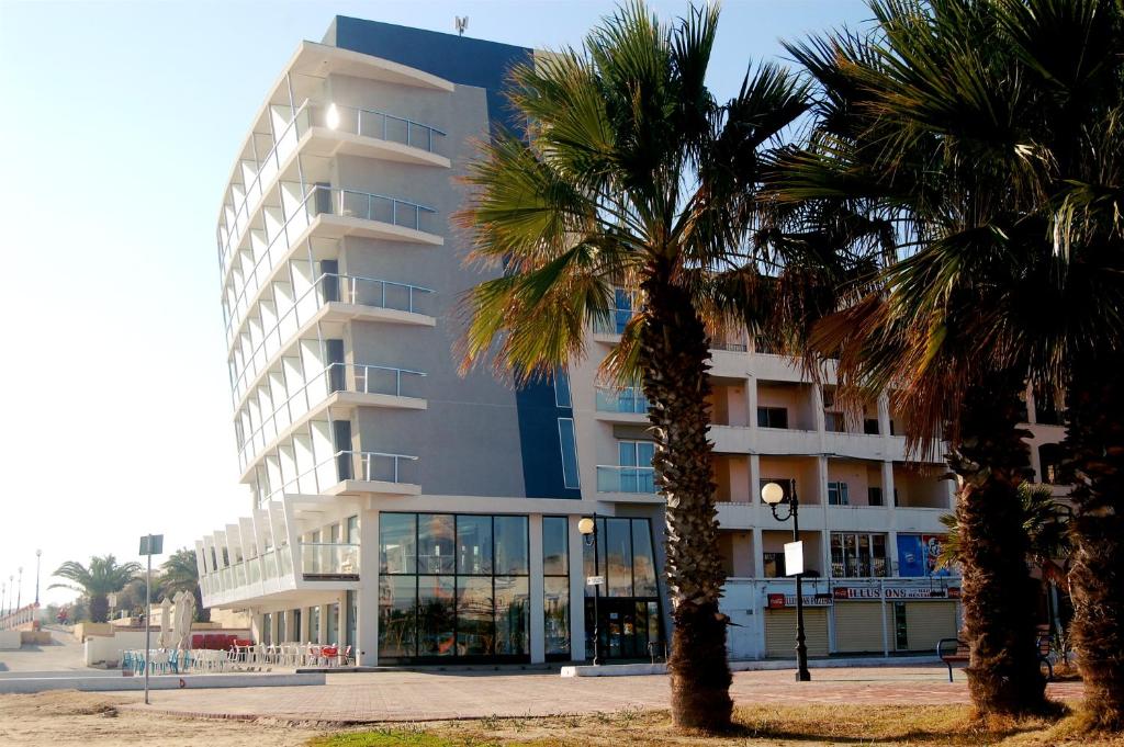 a large building with palm trees in front of it at Water's Edge Hotel in Birżebbuġa