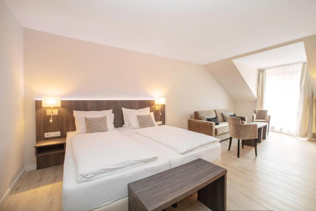 a bedroom with a large white bed and chairs at Hotel Twilling in Sankt Peter-Ording