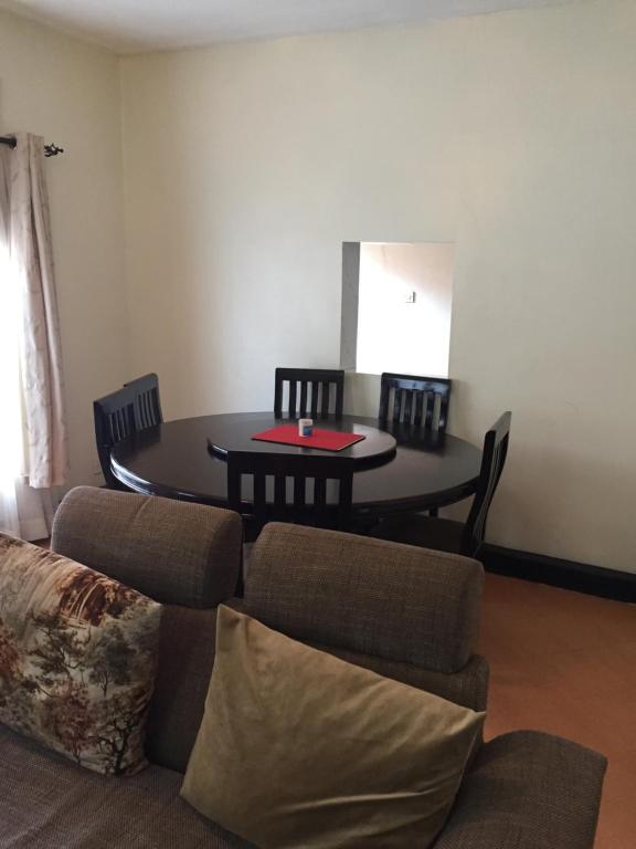 a living room with a table and chairs and a couch at Kampala Ntinda Comfy Holiday Home in Kampala