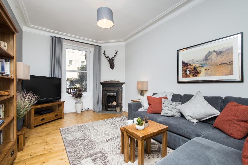 a living room with a couch and a tv at Beautiful, Traditional 2 Bedroom Main Door Flat in Edinburgh