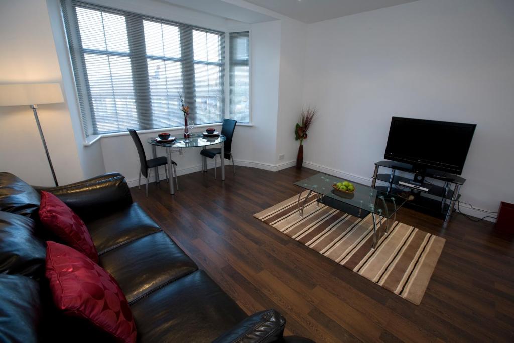 uma sala de estar com um sofá, uma mesa e uma televisão em Aberdeen Serviced Apartments - The Lodge em Aberdeen