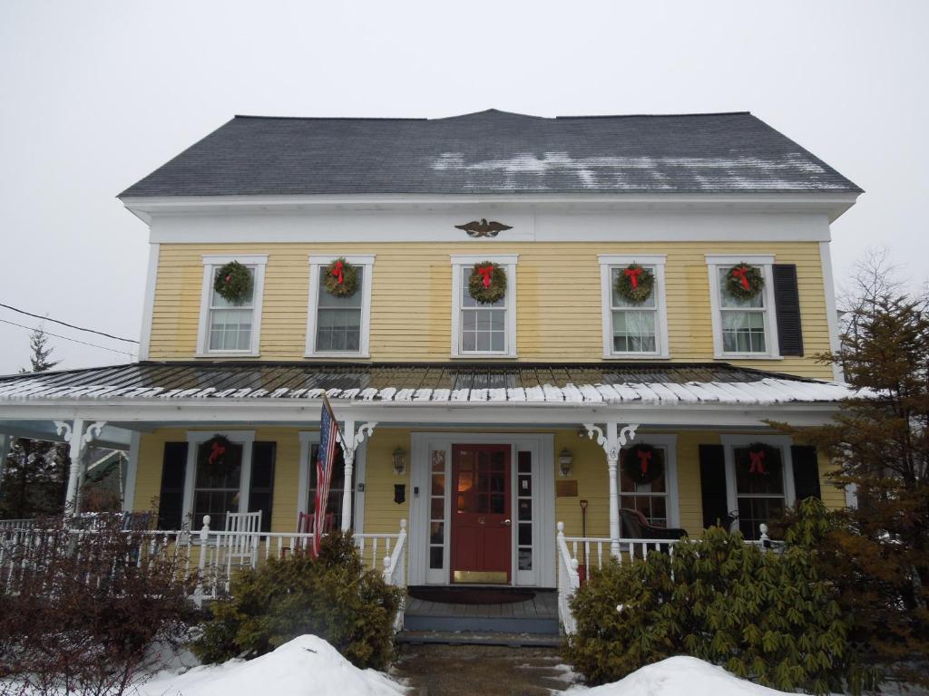 ein gelbes Haus mit Weihnachtskränzen an den Fenstern in der Unterkunft Kearsarge Inn in North Conway