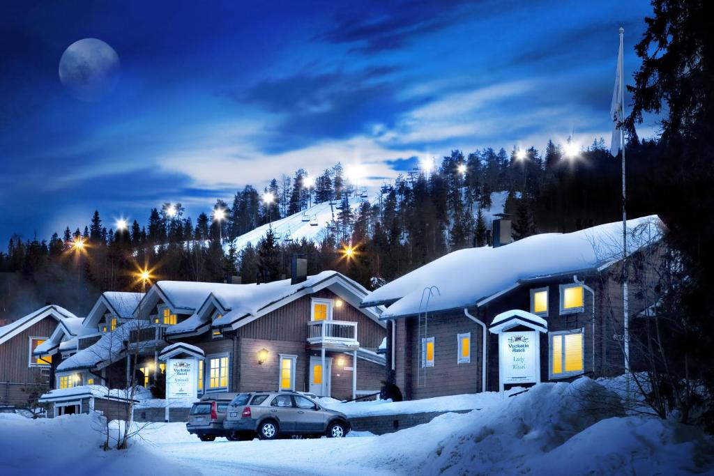 un groupe de maisons dans la neige la nuit dans l'établissement Vuokatin Aateli Apartments, à Vuokatti