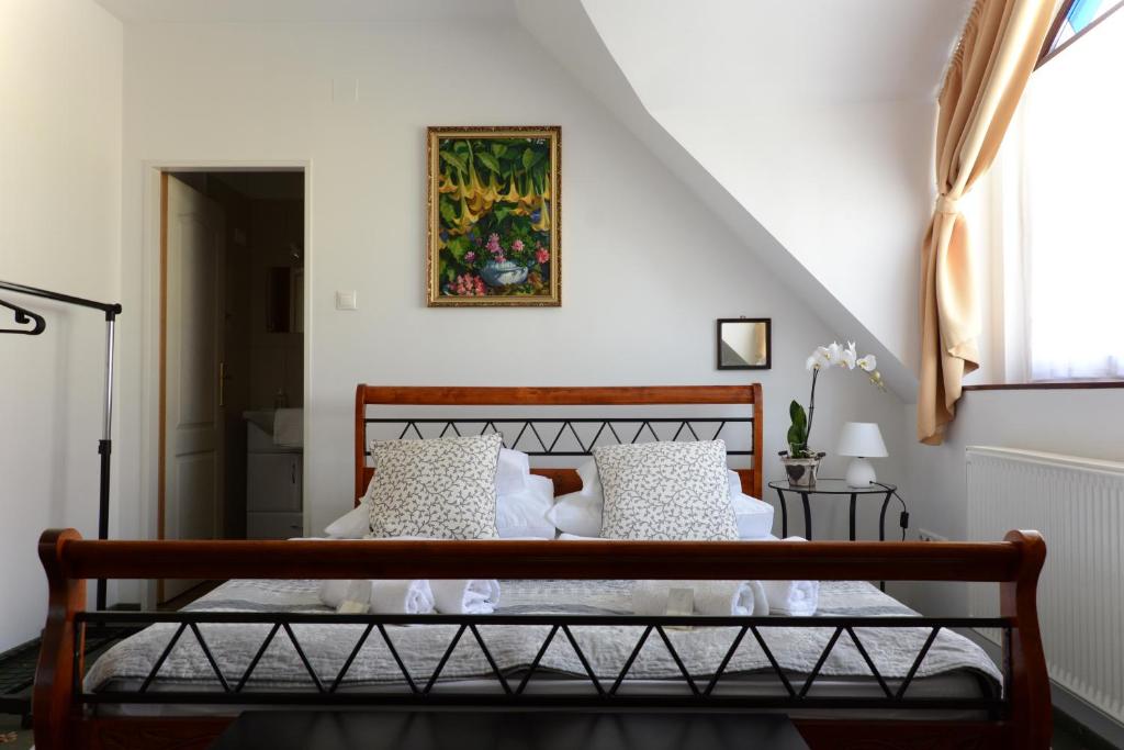 1 dormitorio con cama de madera y almohadas blancas en Malom Vendégház Tapolca, en Tapolca
