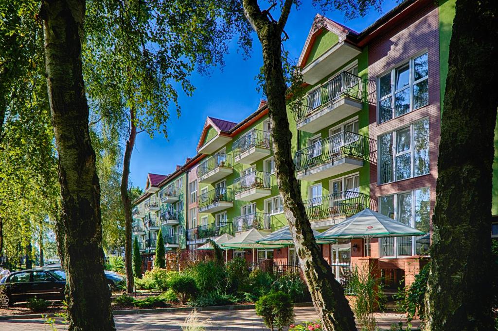 un bâtiment avec des arbres devant lui dans l'établissement Maximus Spa, à Dziwnówek