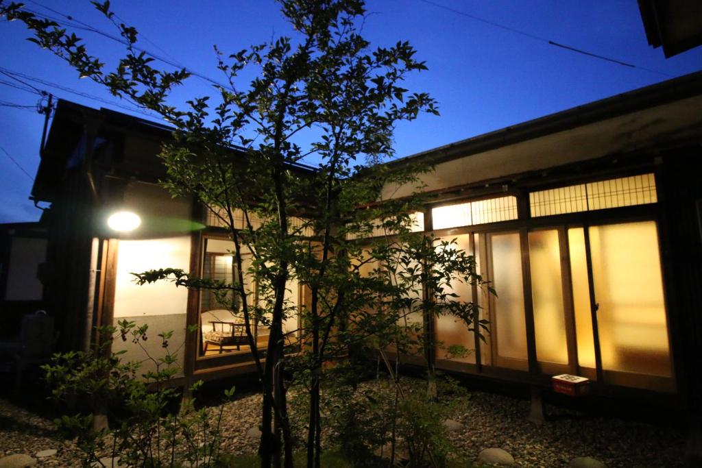 una casa con un árbol delante de ella por la noche en Hostel Fish in a River, en Takayama