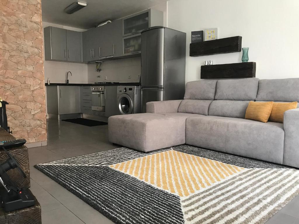 a living room with a couch and a kitchen at Loft-Entre a praia e o campo in Nazaré