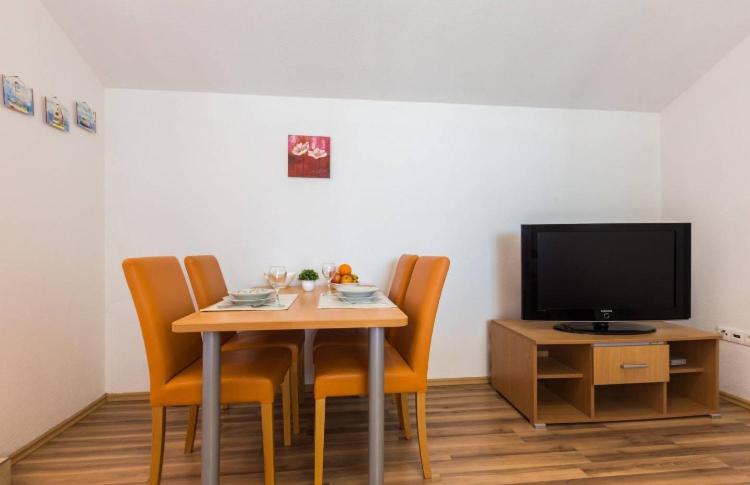 a dining room with a table with chairs and a tv at Slanac 2 in Veli Iž