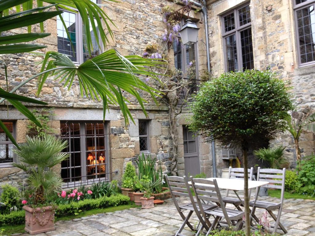 un patio con mesa y sillas frente a un edificio en Hôtel Tanquerey de La Rochaisière, en Coutances