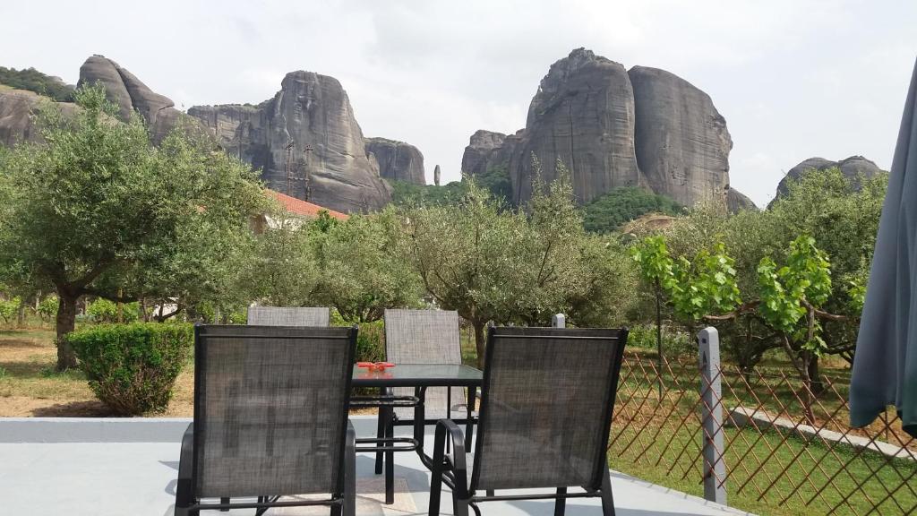a table and chairs with rocks in the background at Olive Grove in Kalabaka