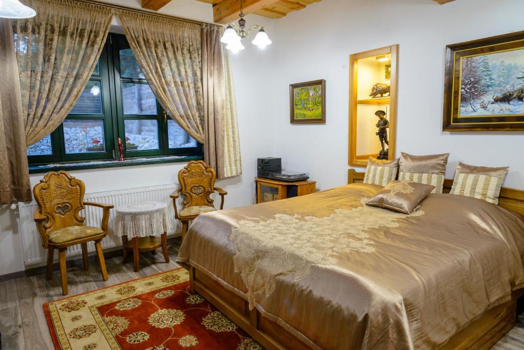 a bedroom with a bed and two chairs and a window at Tündérgyöngye Apartmanház in Zirc