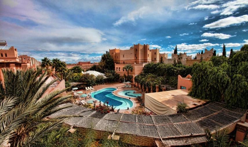 un complexe avec une piscine en face d'un bâtiment dans l'établissement Hotel Club Hanane, à Ouarzazate