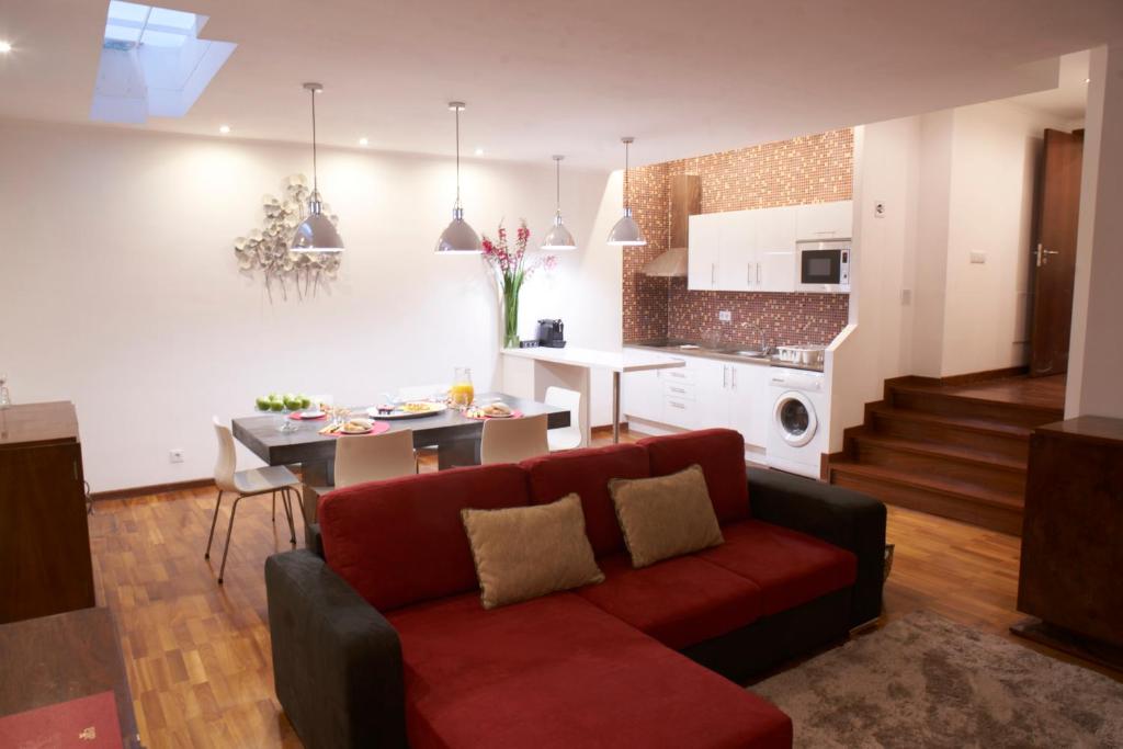 a living room with a red couch and a kitchen at Happily Ever Lisbon in Lisbon