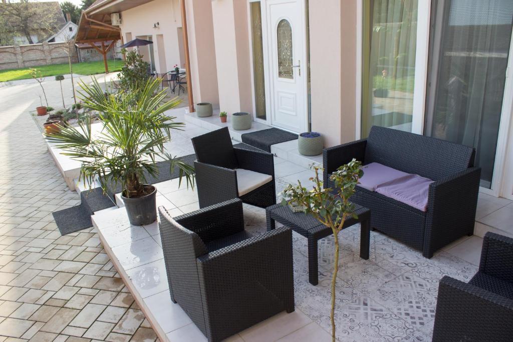 a patio with chairs and tables and potted plants at Makotel Apartmanház in Makó