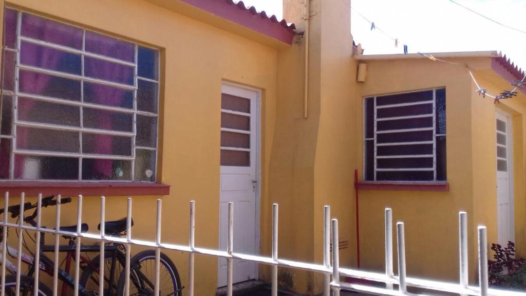 una casa amarilla con una valla delante de ella en Apartamento kitchenette en São Lourenço do Sul