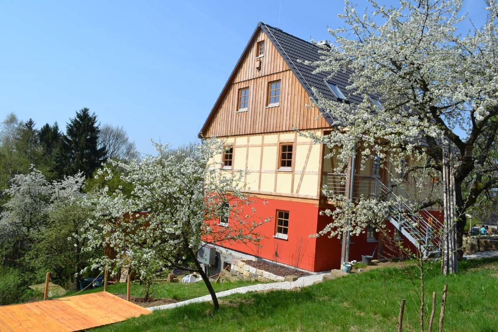 uma casa vermelha e branca com árvores em frente em Ferienwohnung Brox em Sebnitz